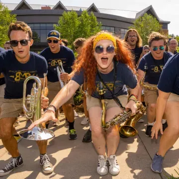 Members of the marching band cheer and pose for a photo with their instruments and matching t-shirts